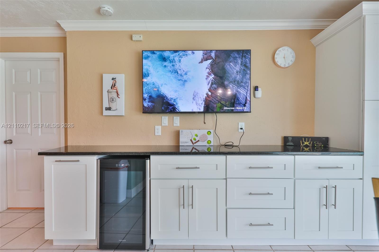 Built-in cabinetry featuring white shaker-style doors and drawers, dark stone-finish countertop, brushed nickel hardware, and dedicated beverage refrigerator niche