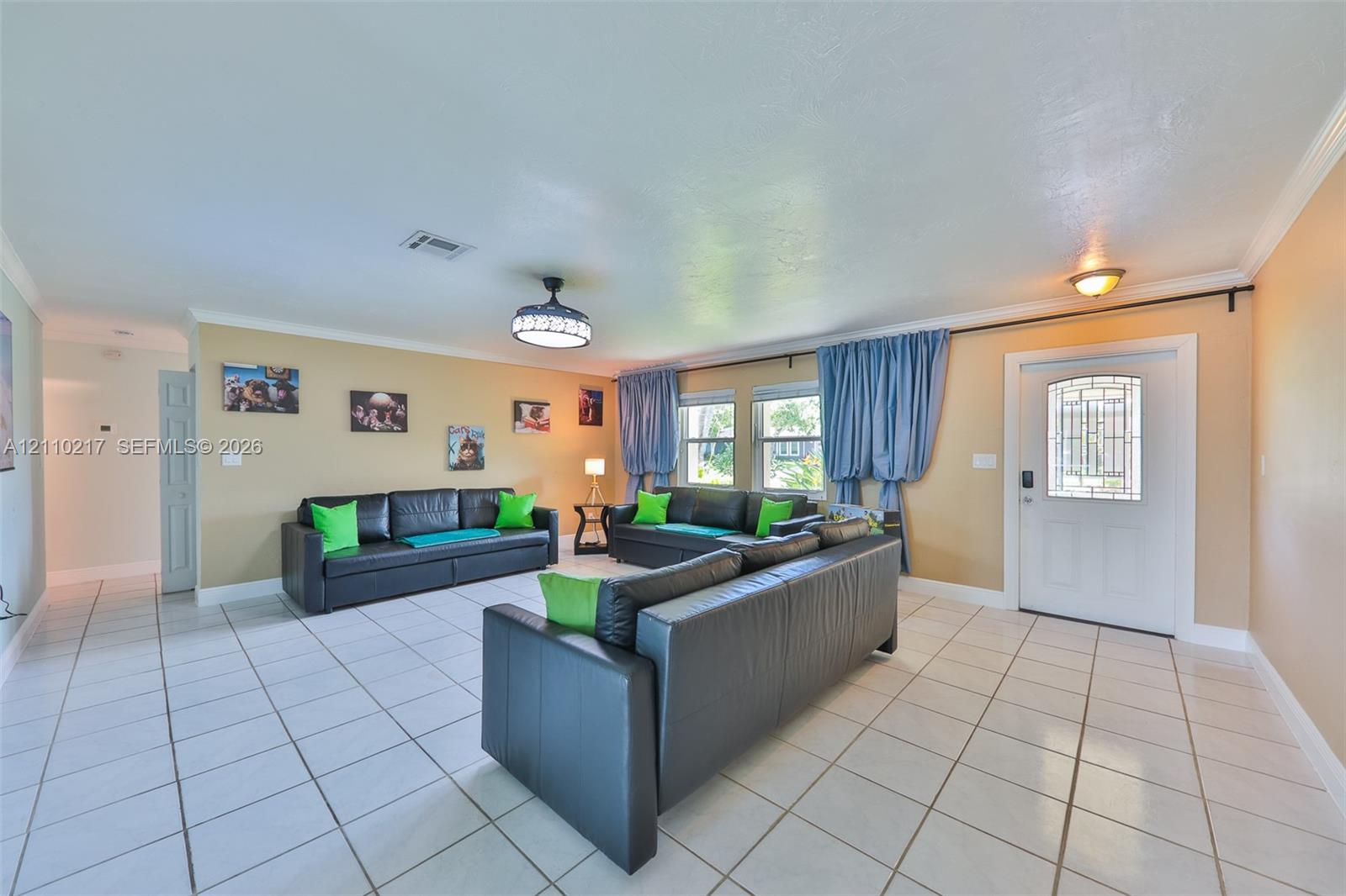 Spacious interior featuring large-format white tile flooring, recessed lighting, a modern ceiling fan with integrated lighting, and an entry door with decorative glass paneling