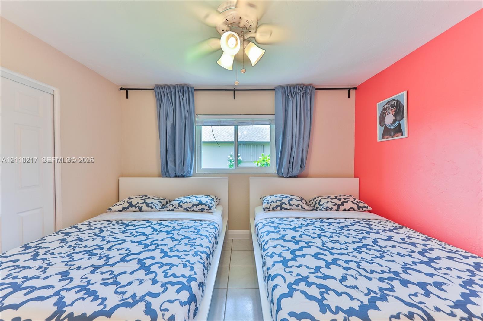 Room featuring neutral wall tones, a bold accent wall, ceramic tile flooring, and a ceiling-mounted light fixture with a central fan