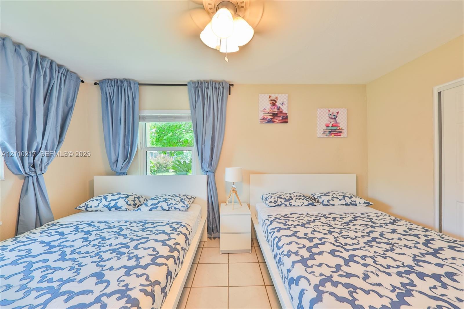 Room featuring neutral-toned walls, tiled flooring, a multi-light ceiling fixture, and a window with a curtain rod assembly