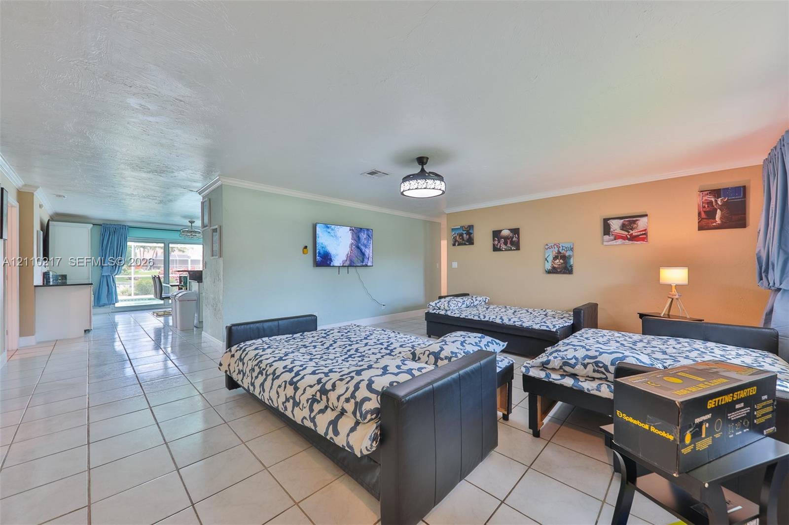 Open-concept living space featuring large-format tile flooring, a mounted ceiling fan with integrated lighting, and sliding glass doors
