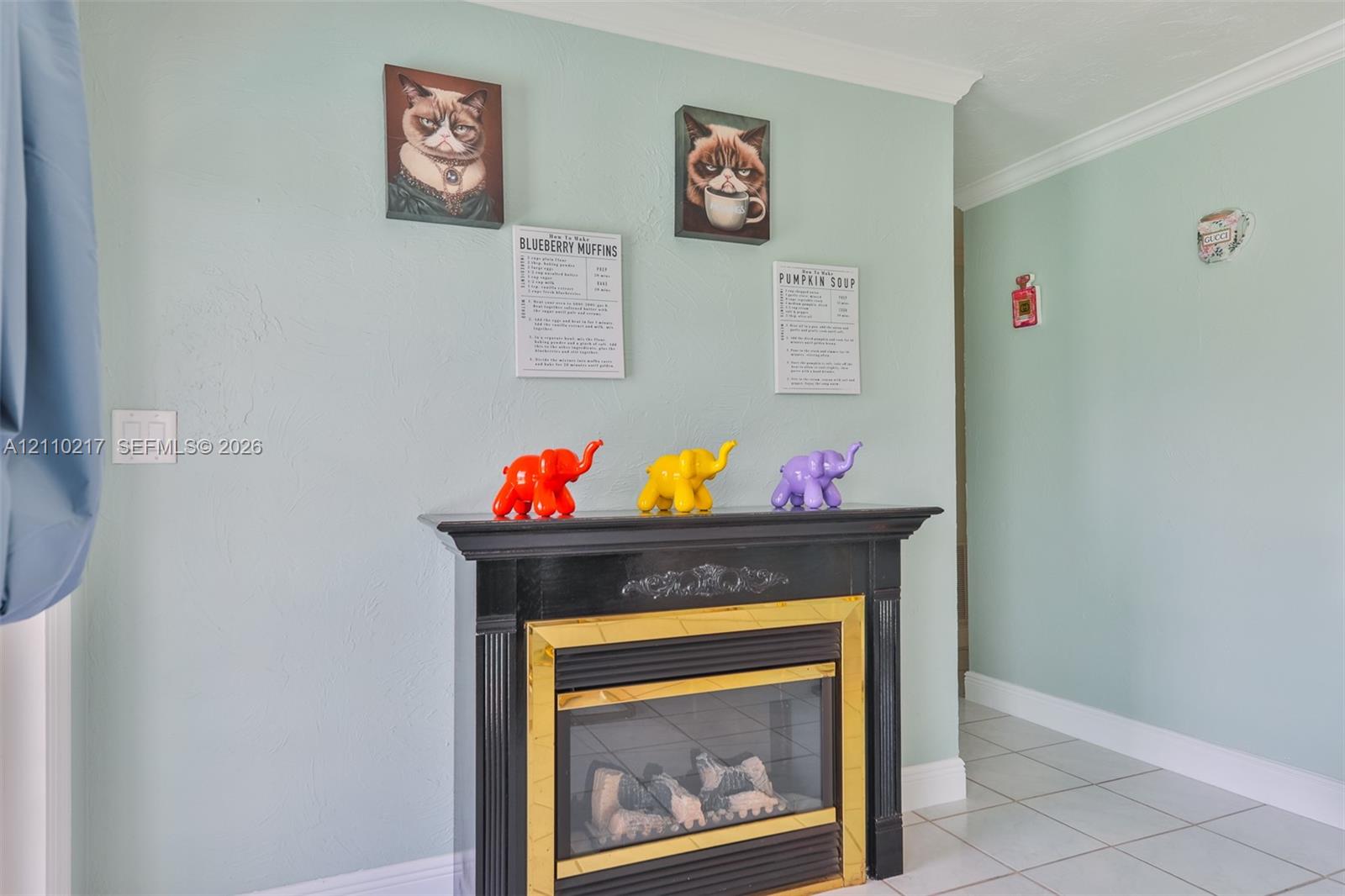Fireplace featuring a black mantel, brass-tone surround, and crown molding
