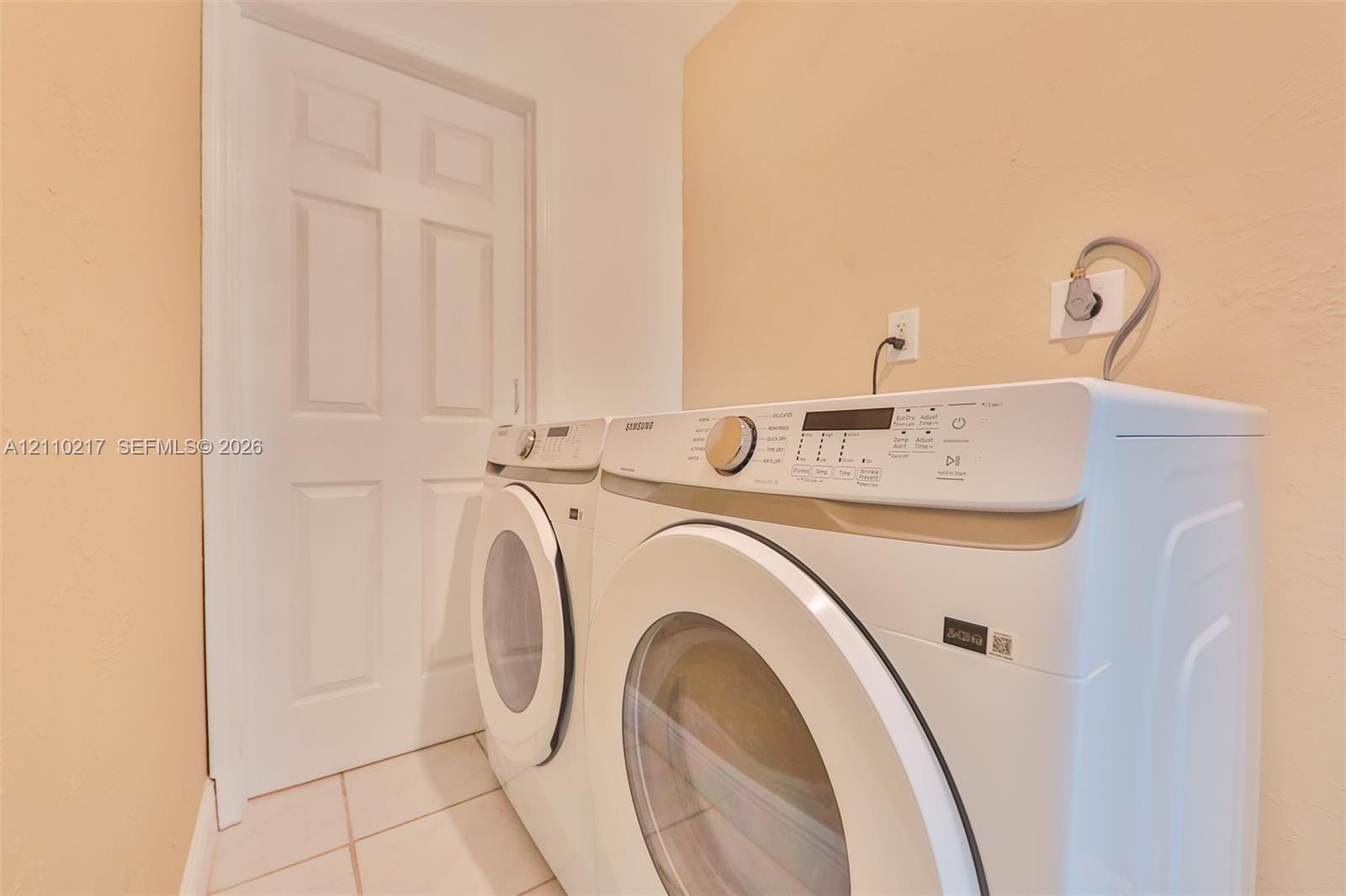 Dedicated utility area featuring tile flooring, a solid-core interior door, and hookups for laundry appliances