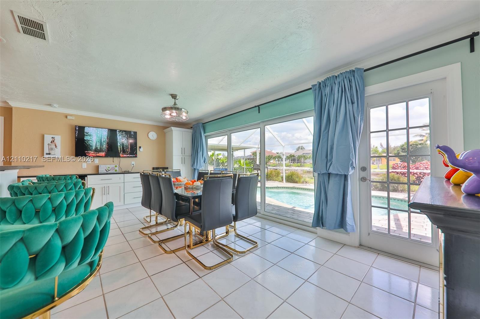 Ceramic tile flooring, built-in cabinetry with dark countertops, three-panel sliding glass doors, and a full-light glass entry door opening to an enclosed pool area