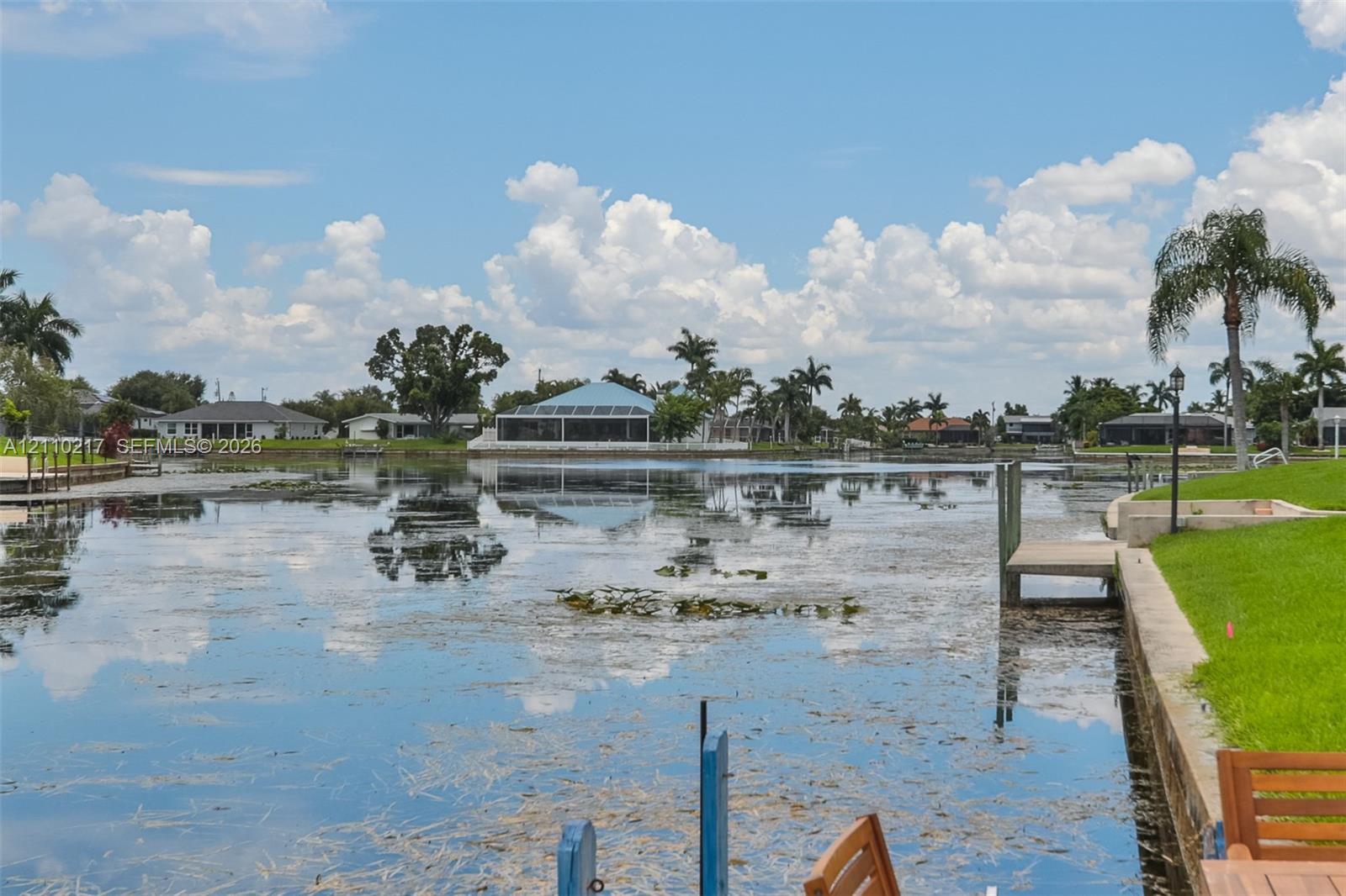 Waterfront property featuring a concrete seawall, private dock, and manicured lawn