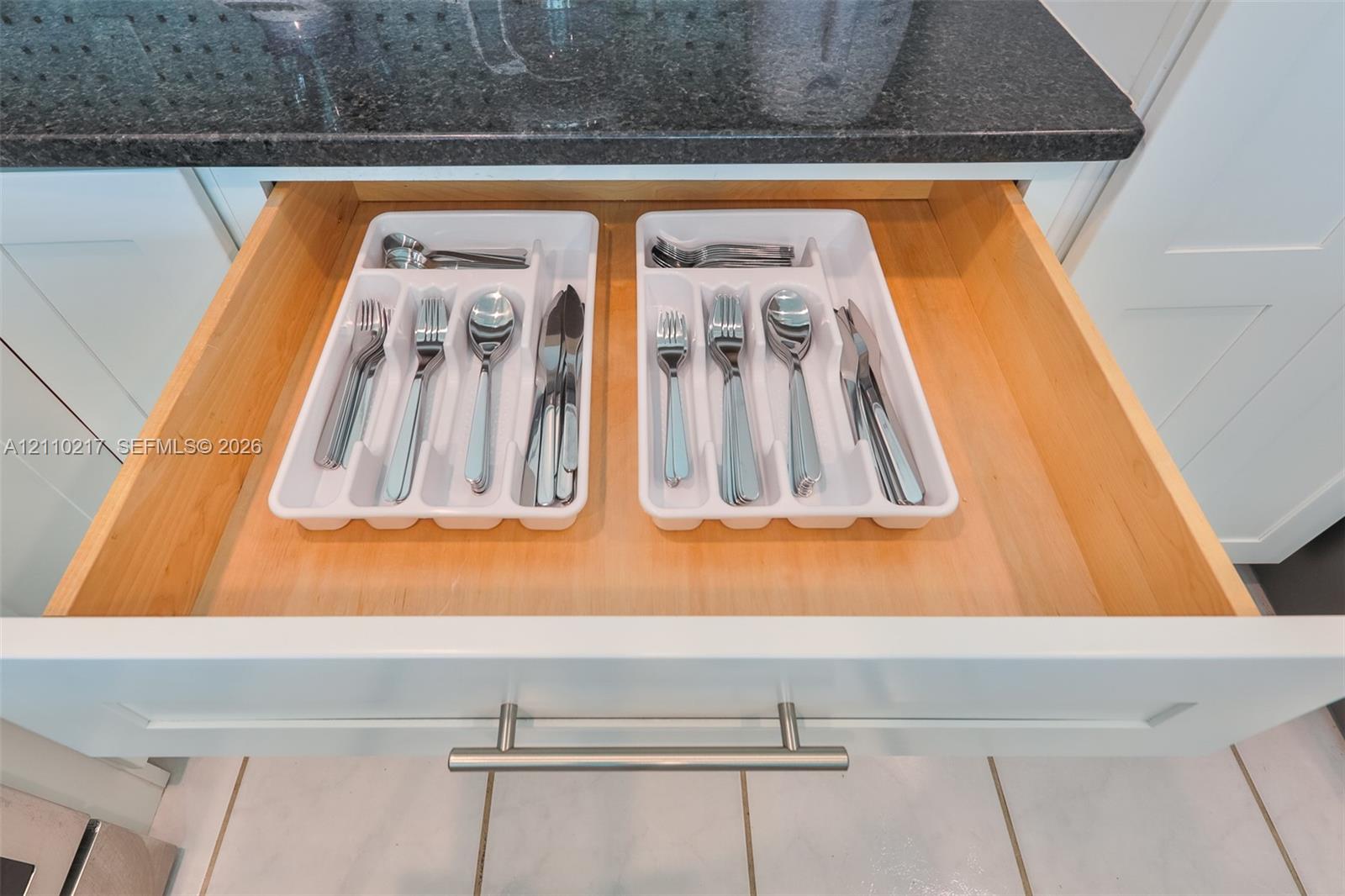Drawer featuring natural wood-finish construction, brushed metal bar hardware, and solid-surface countertop