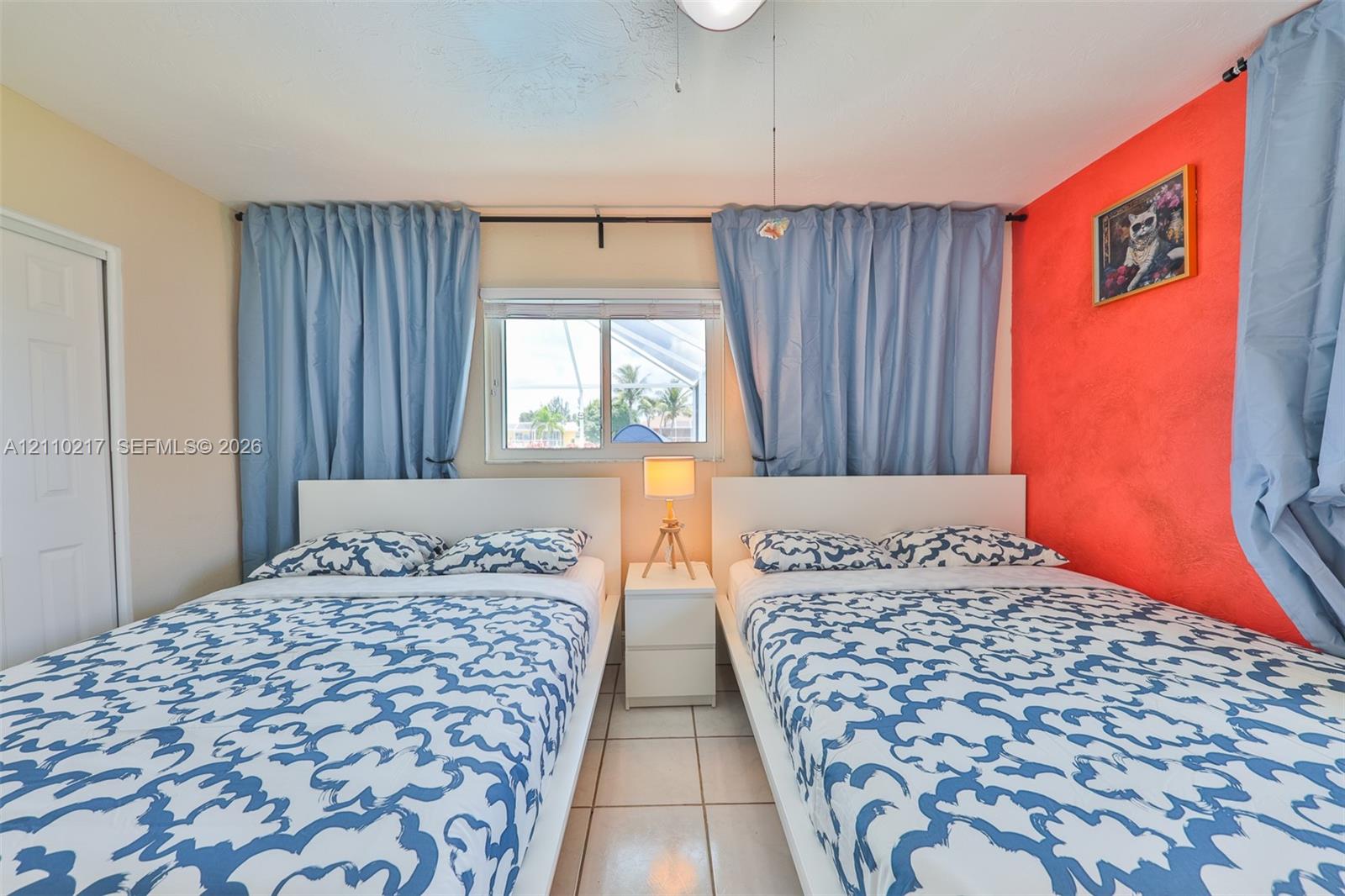 Room featuring white tiled flooring, a single-panel interior door, and a sliding window with a horizontal metal frame