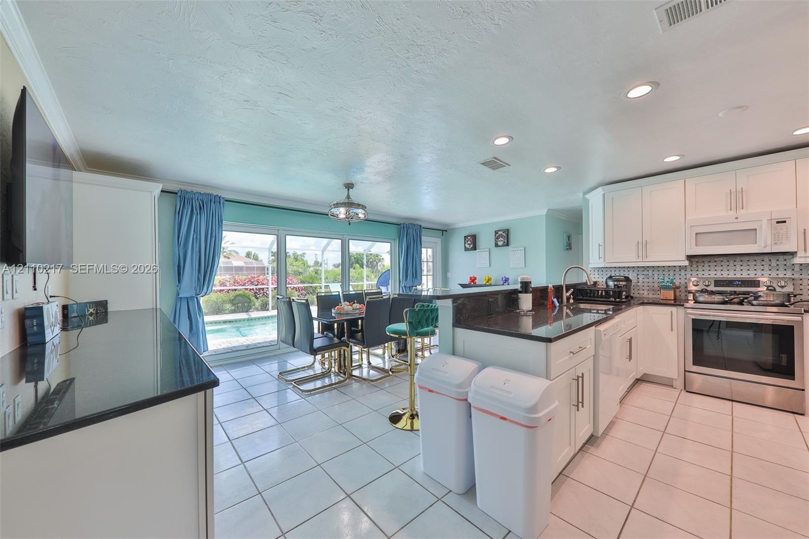 Kitchen featuring white cabinetry, dark countertops, a stainless steel range, ceramic tile flooring, and large sliding glass doors