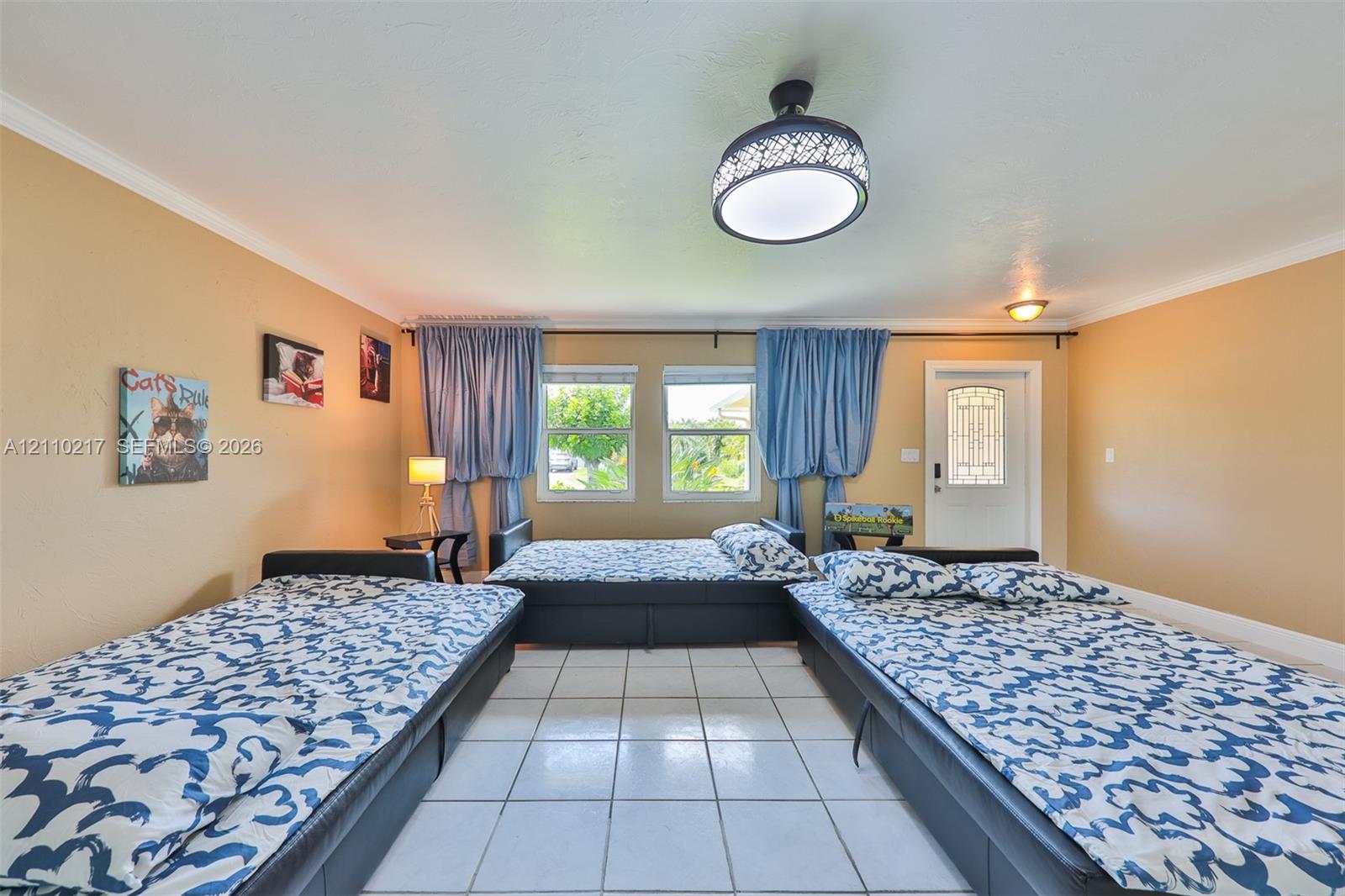 Tiled flooring, dual windows with curtain hardware, flush-mount decorative ceiling lighting, and an exterior door with a glass inlay panel