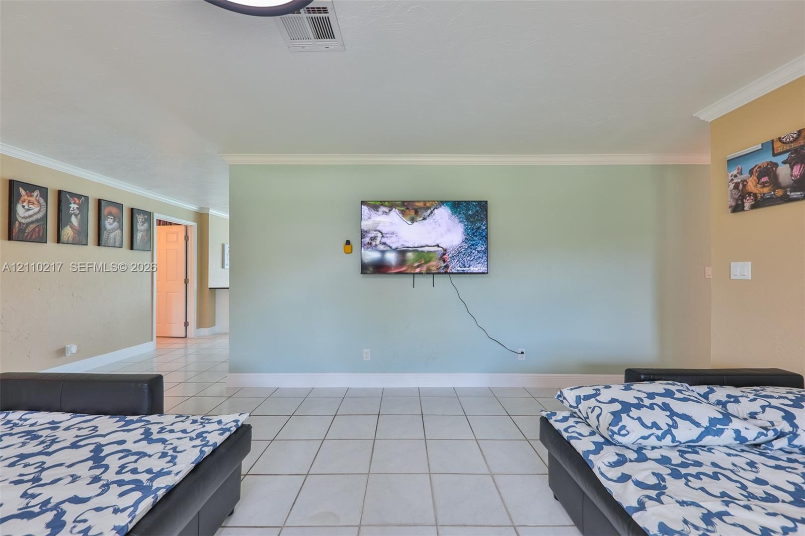 Interior space featuring white tiled flooring, crown molding, and an accent wall