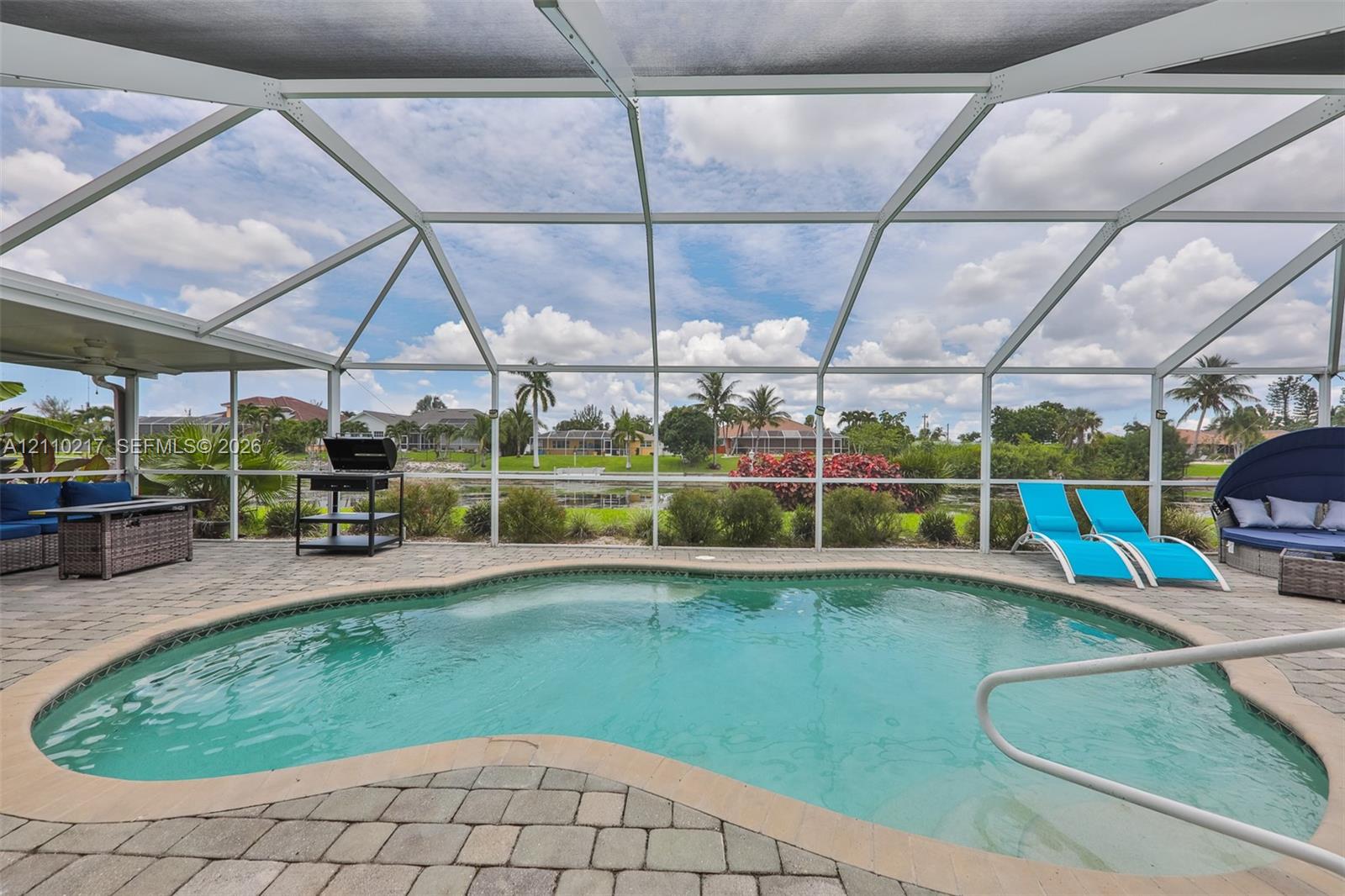 Screen-enclosed patio featuring a curved swimming pool, paver hardscaping, and a white aluminum frame