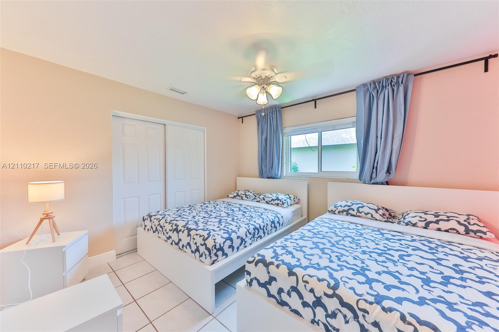 Room featuring tile flooring, sliding closet doors, and a ceiling-mounted light fixture with a fan