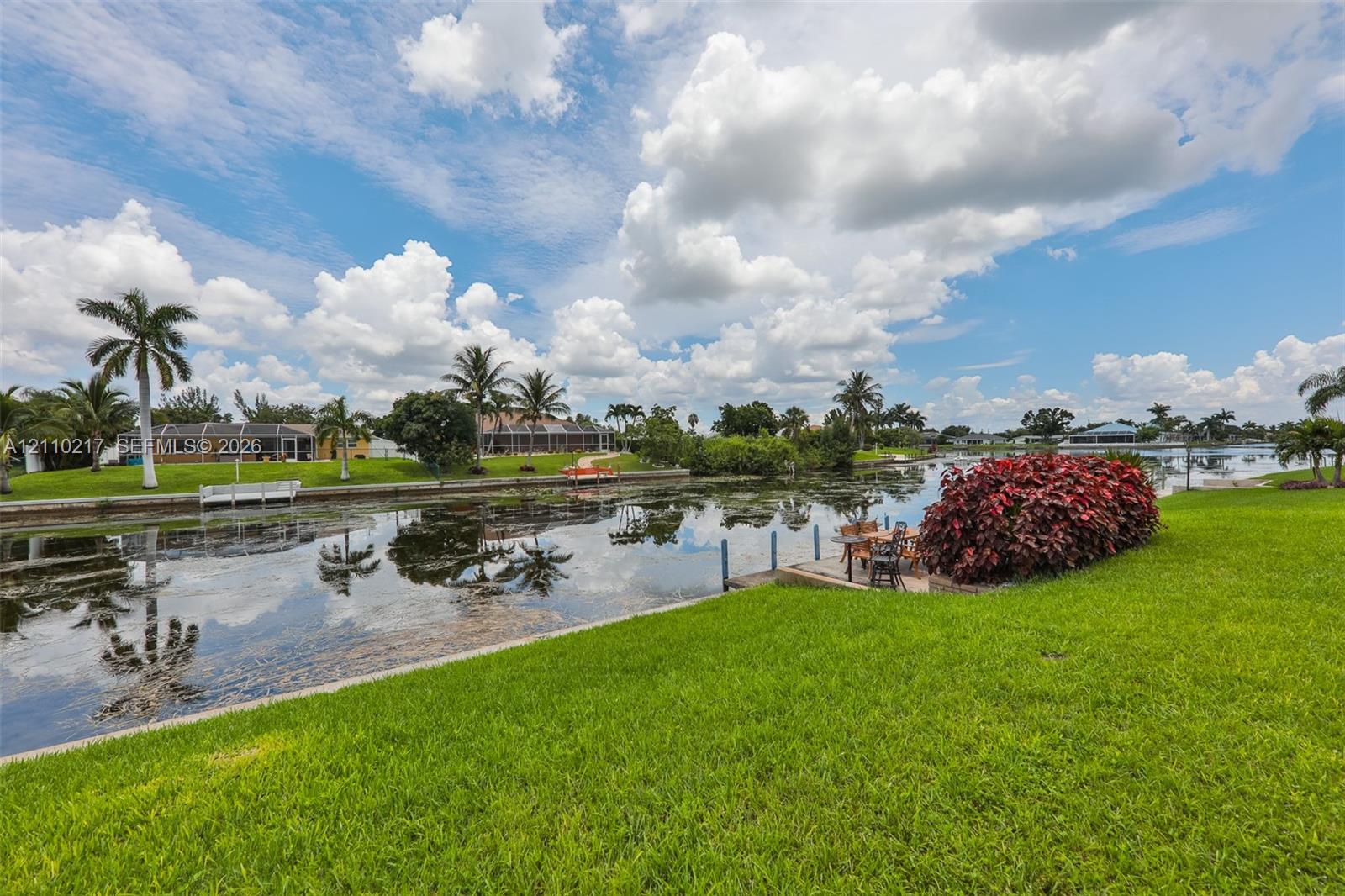 Waterfront lot featuring a manicured lawn, stone bulkhead, and integrated dock