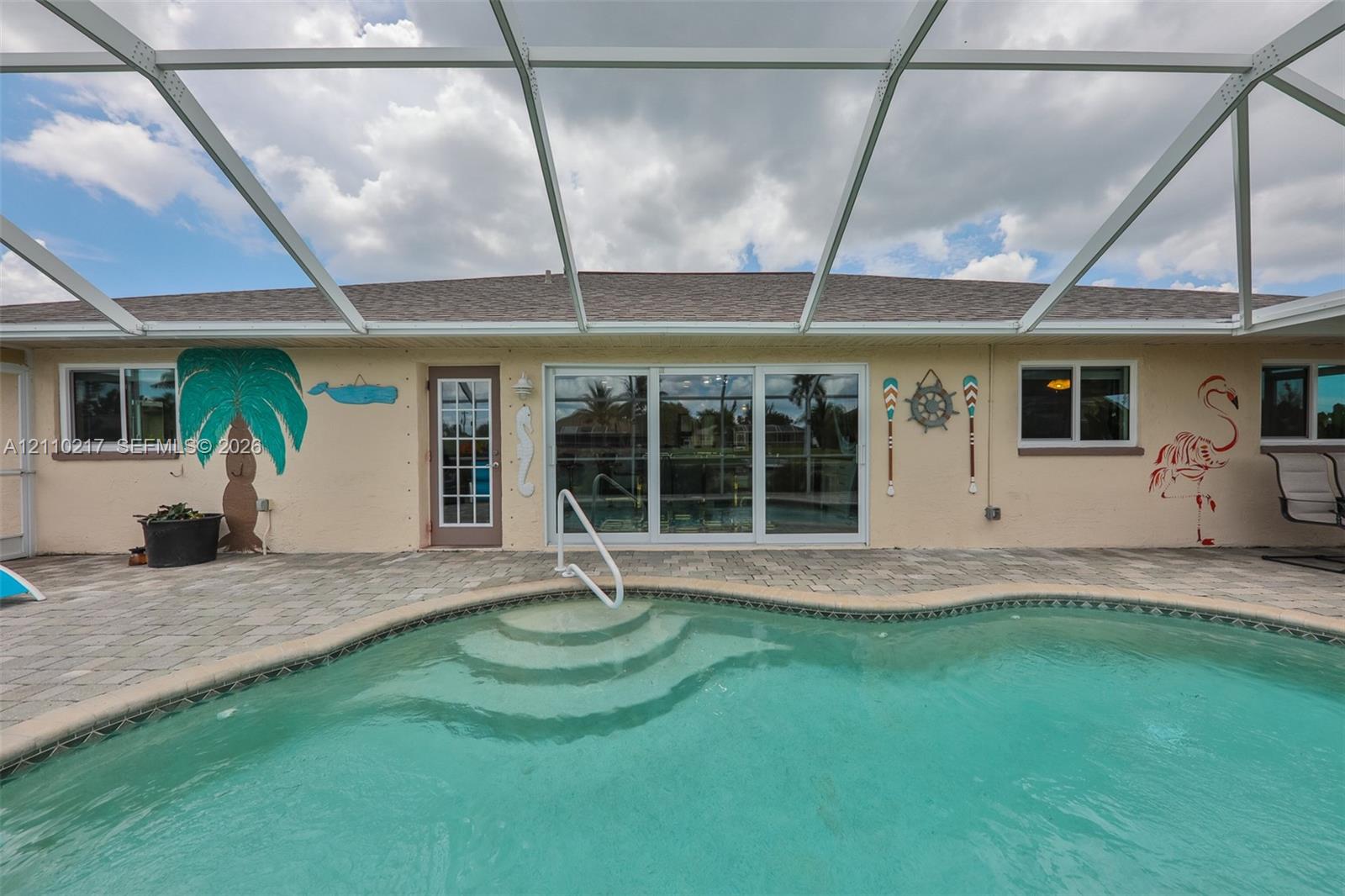 Screen-enclosed pool area featuring a paver patio, integrated pool steps, and sliding glass door access