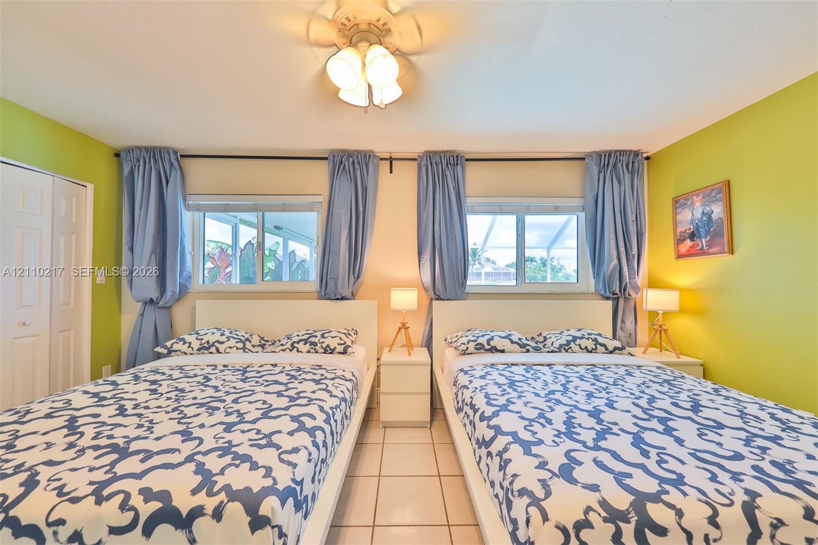 Two dual-pane sliding windows, ceramic tile flooring, ceiling fan with glass-shade light fixture, and paneled closet doors