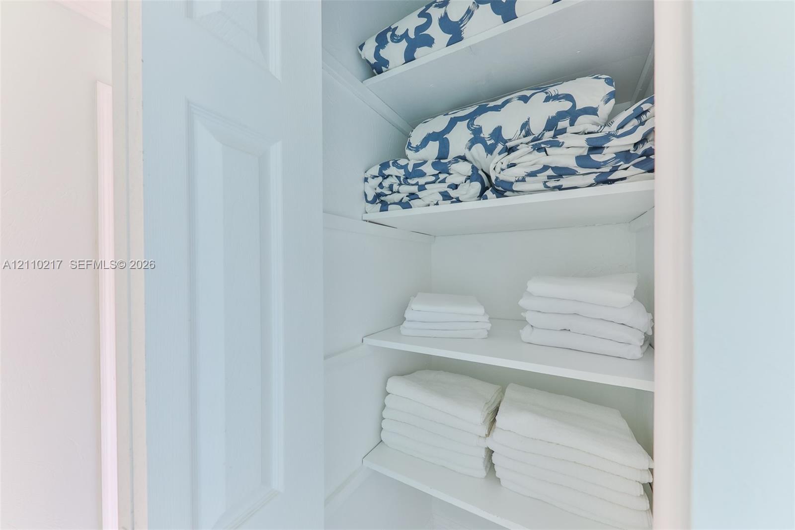Storage closet featuring white interior finishes and four built-in shelves