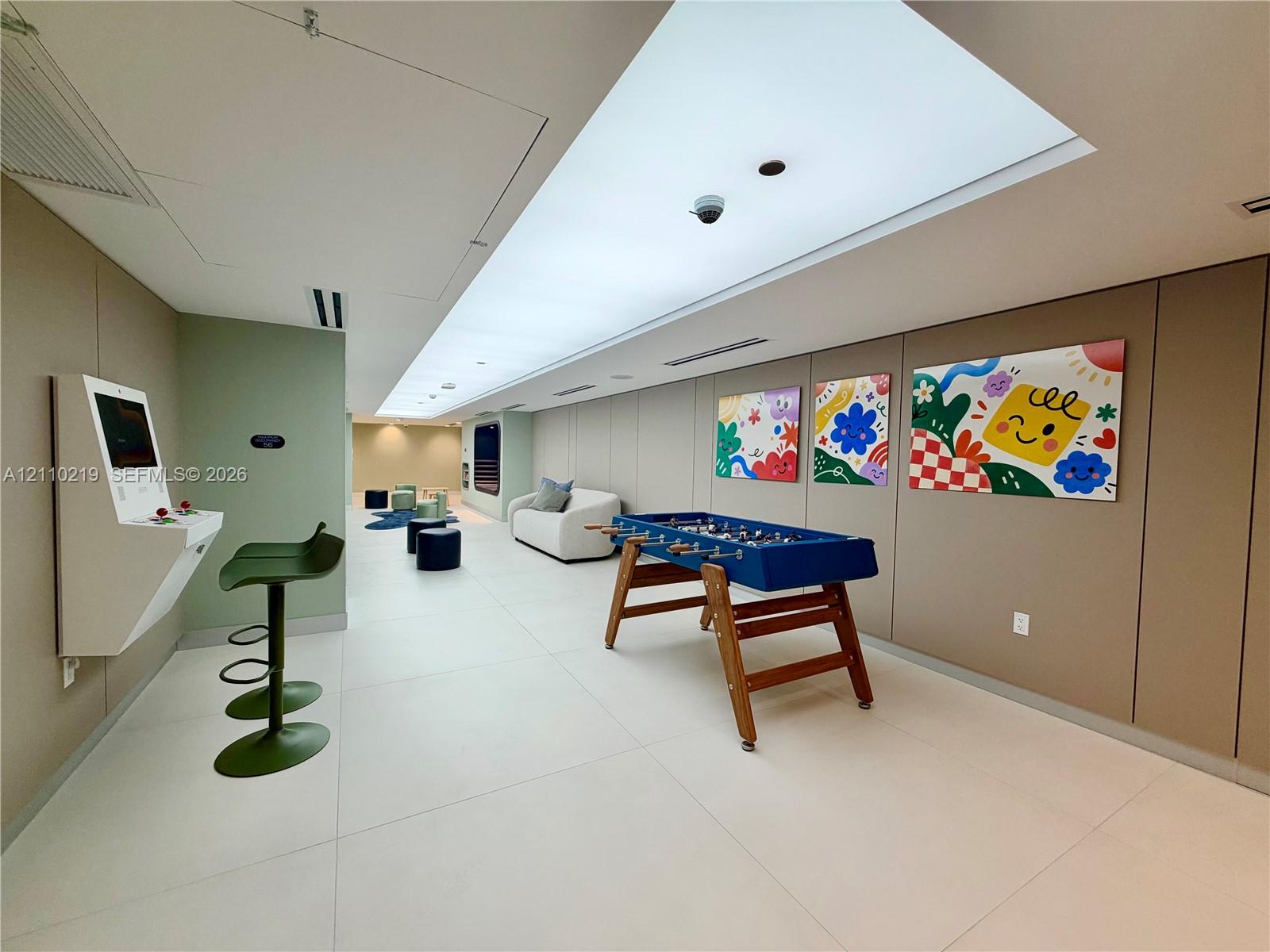 Large-format tile flooring, recessed linear ceiling lighting, and smooth-finish wall paneling
