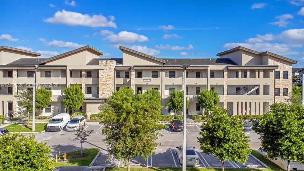 Multi-story exterior featuring a contemporary shed roofline, neutral stucco facade, stone veneer accents, and recessed private balconies