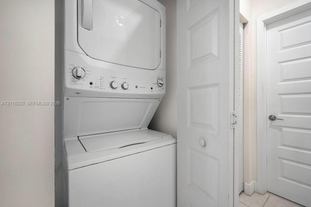 Stacked washer and dryer unit, louvered bi-fold closet doors, and solid-core paneled interior door