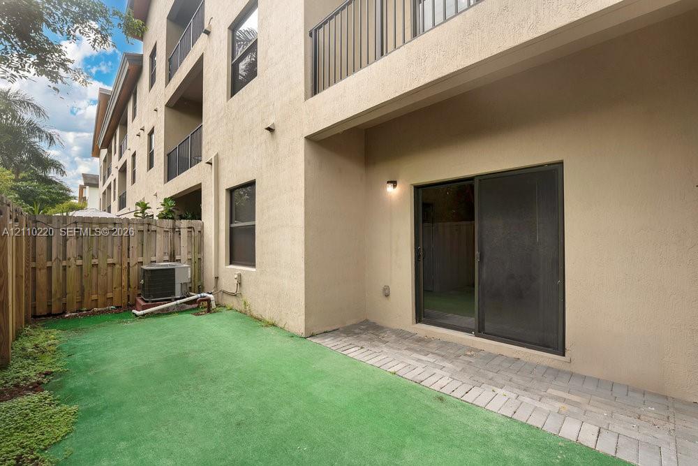 Private ground-level patio featuring paver accents, a sliding glass door entry, and wood-style privacy fencing