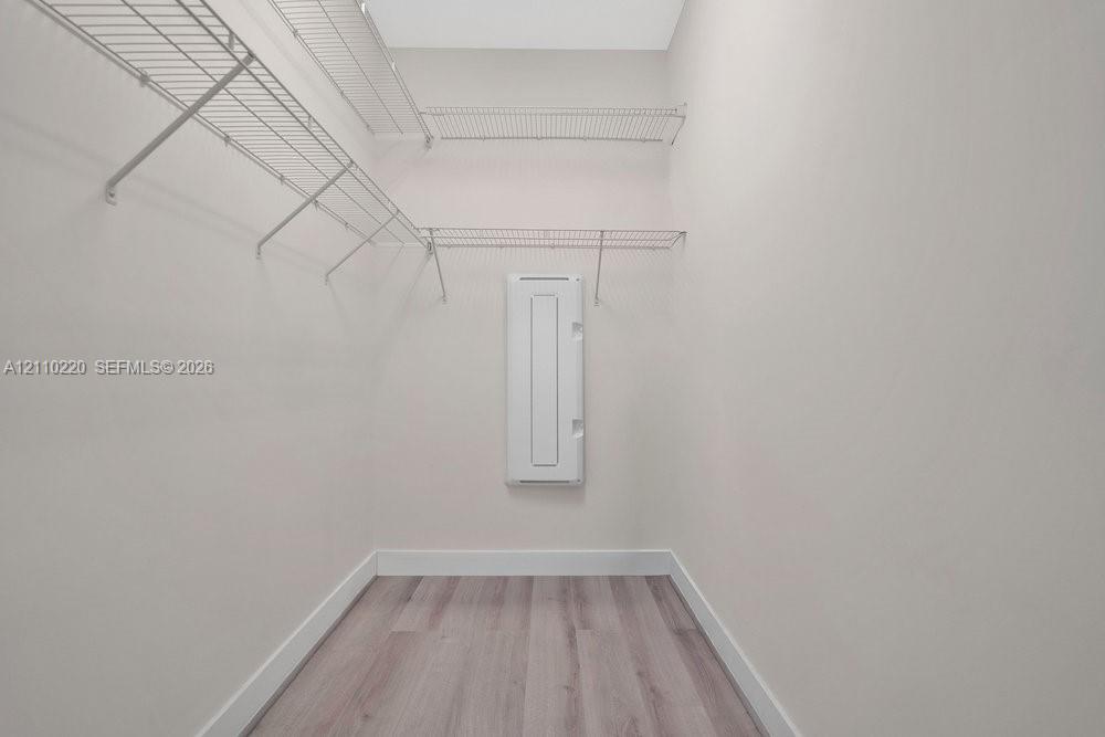 Storage space featuring tiered wire shelving and wood-finish flooring