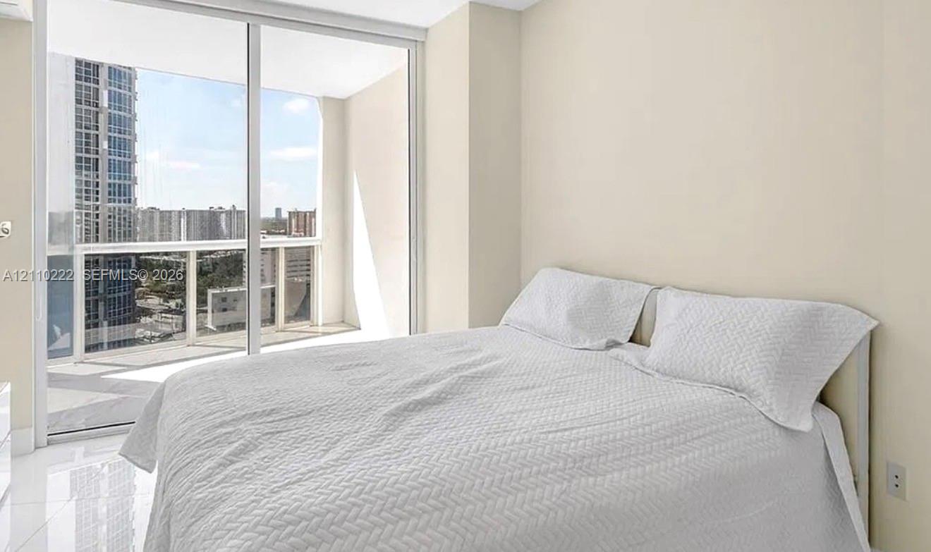 Floor-to-ceiling glass sliding doors, private balcony, neutral wall palette, and polished tile flooring Floor-to-ceiling glass sliding doors, private balcony, neutral wall palette, and polished tile flooring
