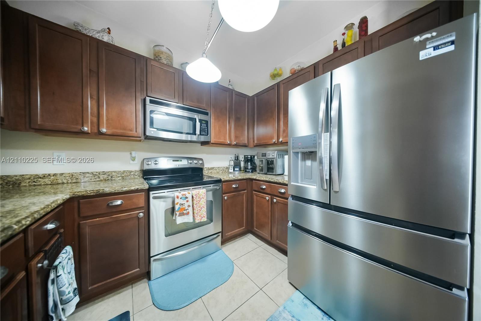 Kitchen featuring shaker-style cabinetry, stone-finish countertops, stainless steel appliances, and ceramic tile flooring
