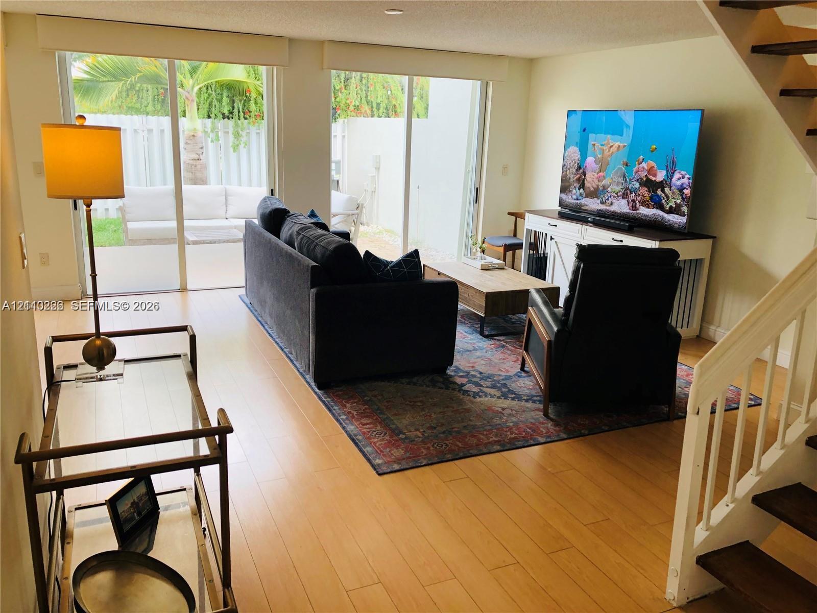 Open-concept living space featuring wood-finish flooring and a staircase with white balusters and wood handrails