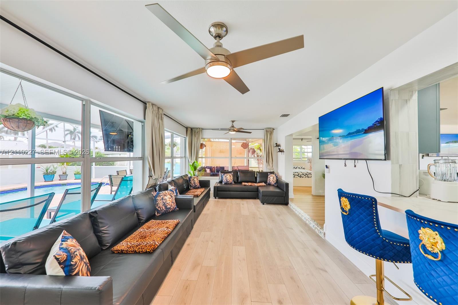 Light-filled interior featuring wood-finish flooring, dual ceiling fans, and a pass-through breakfast bar