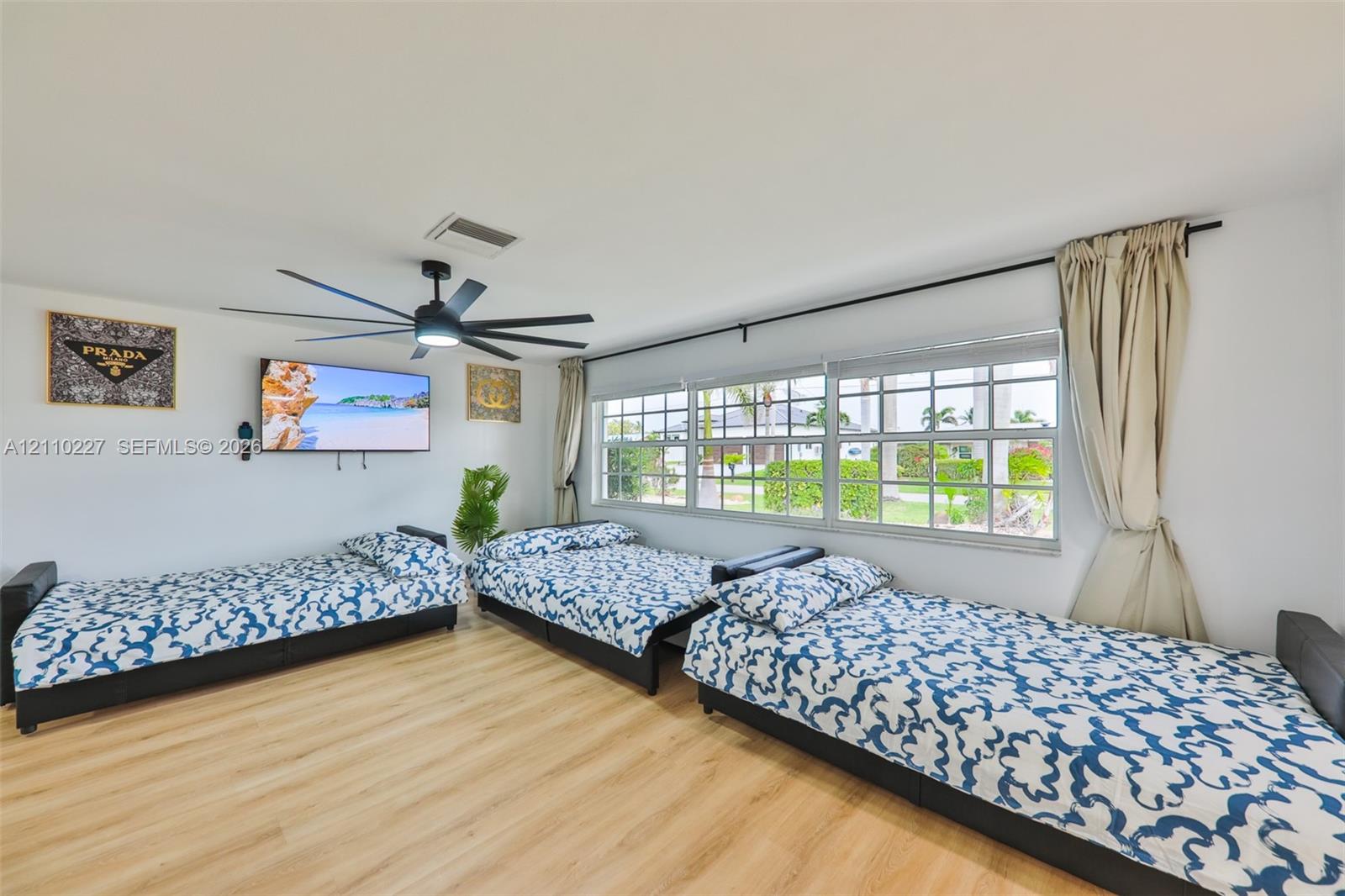 Wood-finish flooring, multi-pane windows, and a large-diameter ceiling fan with integrated lighting