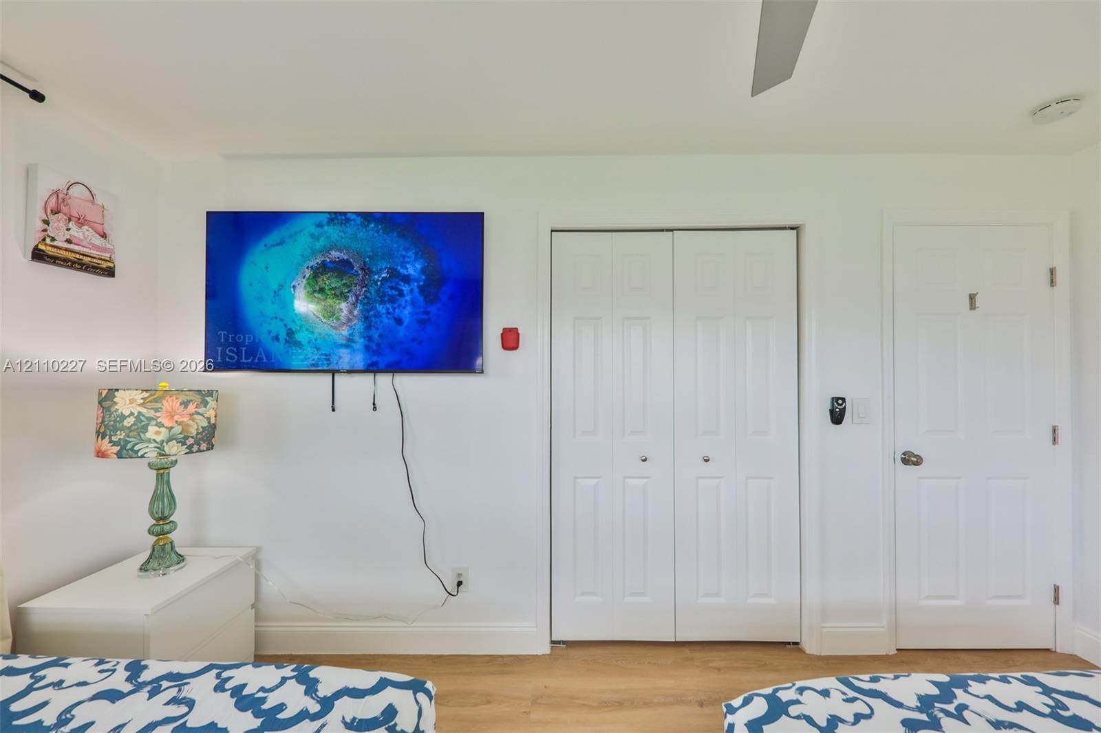 Wood-finish flooring, double-panel closet doors, and interior paneled door featuring brushed-nickel hardware