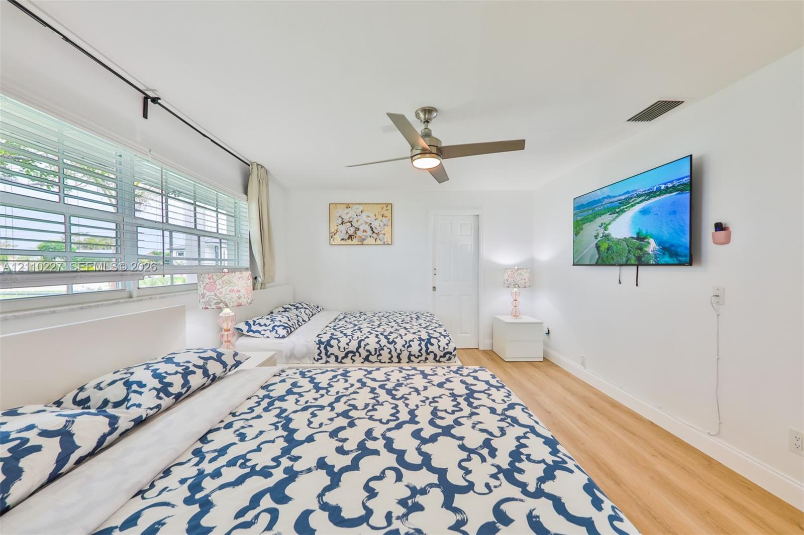 Interior space featuring wood-finish flooring, a multi-pane horizontal window, and a brushed nickel ceiling fan with integrated lighting