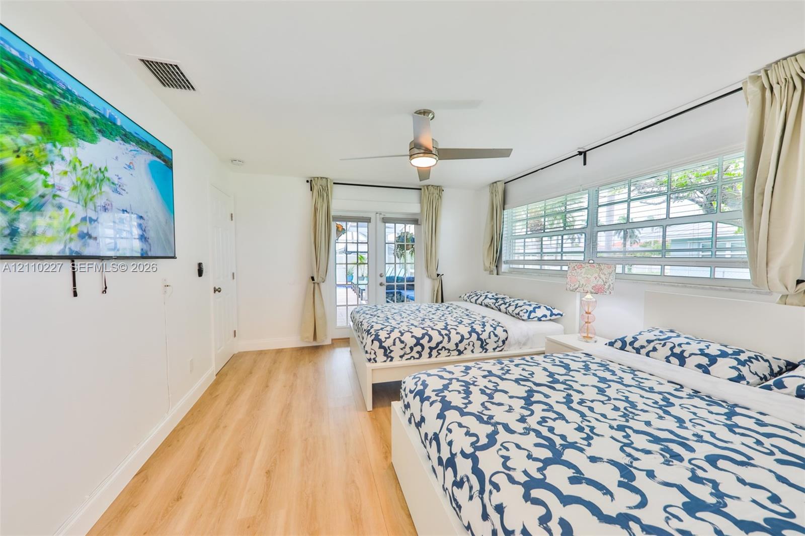 Bright room featuring wood-finish flooring, a contemporary ceiling fan, and multi-pane glass french doors