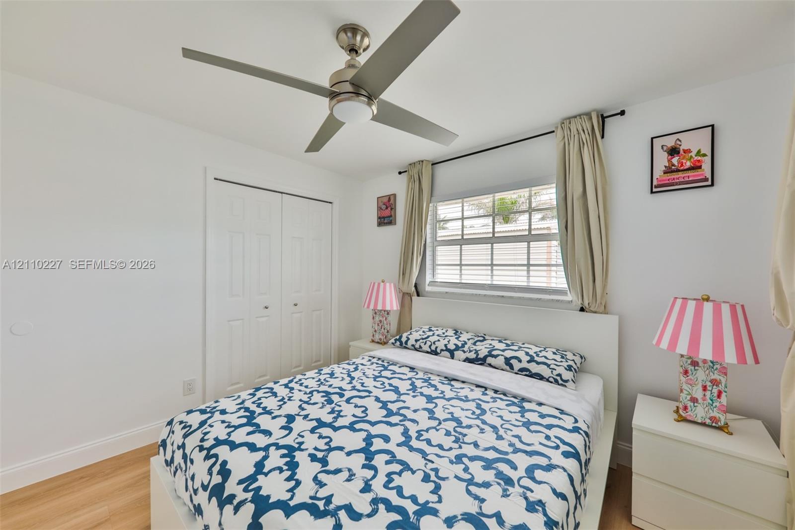 Wood-finish flooring, brushed nickel ceiling fan with integrated lighting, dual-panel closet doors, and multi-pane horizontal window