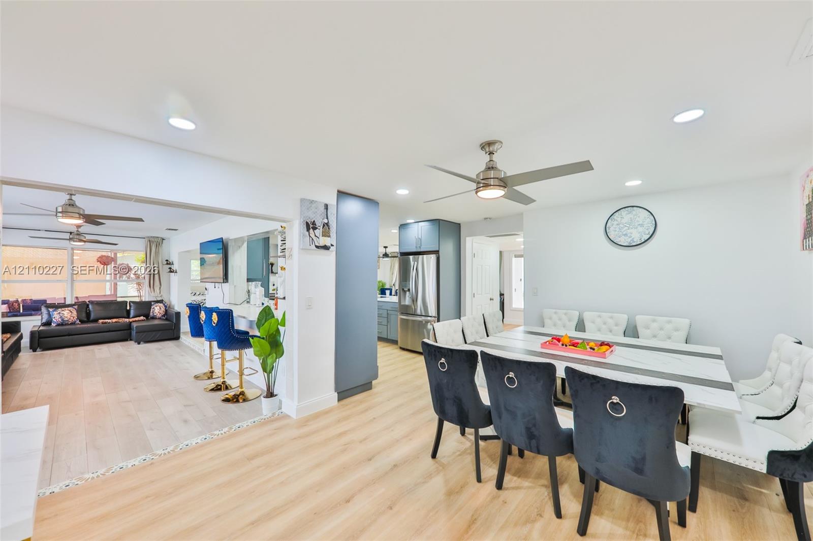 Open-concept interior featuring light wood-finish flooring, recessed lighting, matte-finish cabinetry, stainless steel kitchen appliances, and ceiling fans