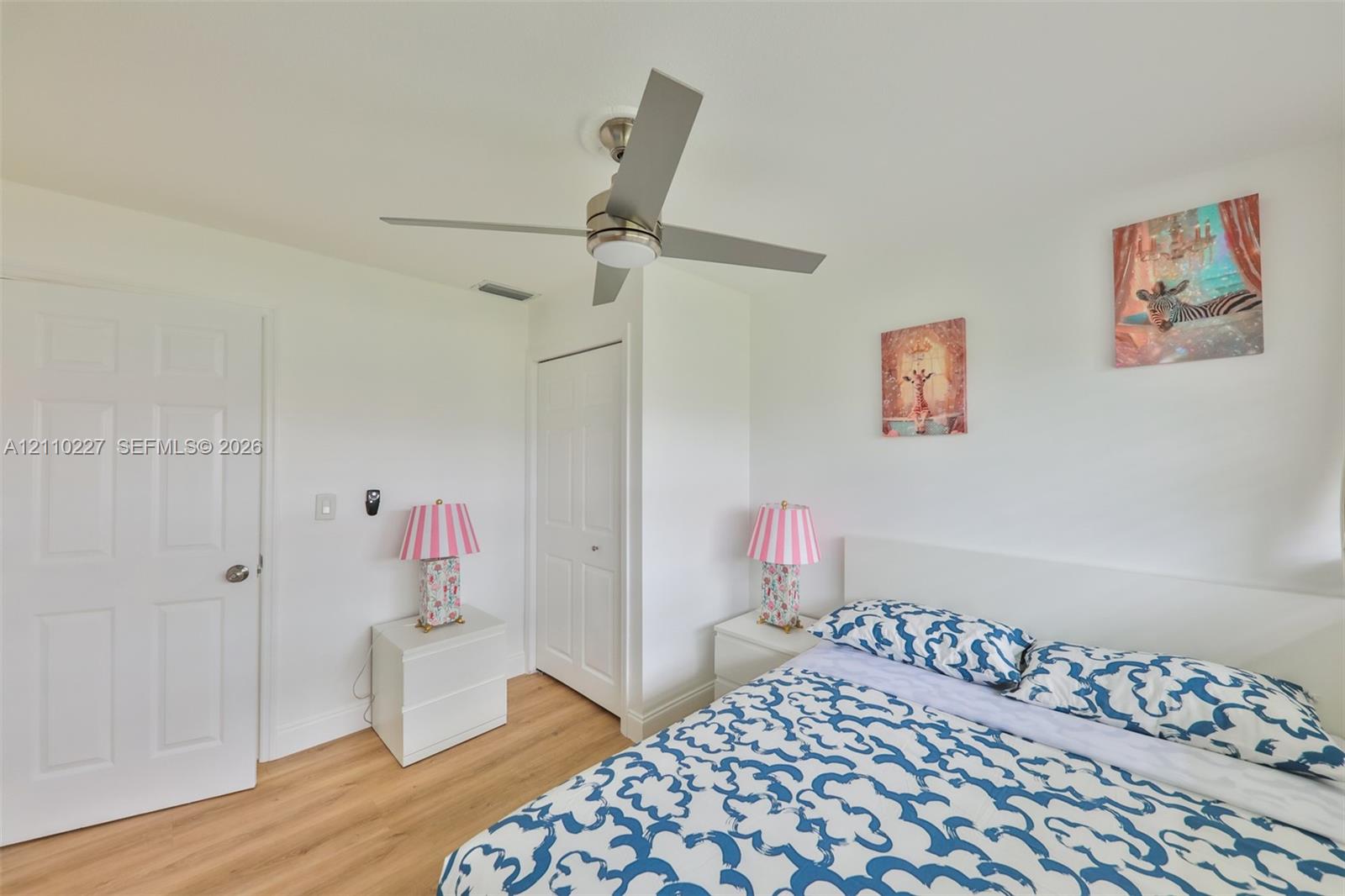 Wood-finish flooring, brushed nickel ceiling fan with integrated light fixture, and two-panel interior doors
