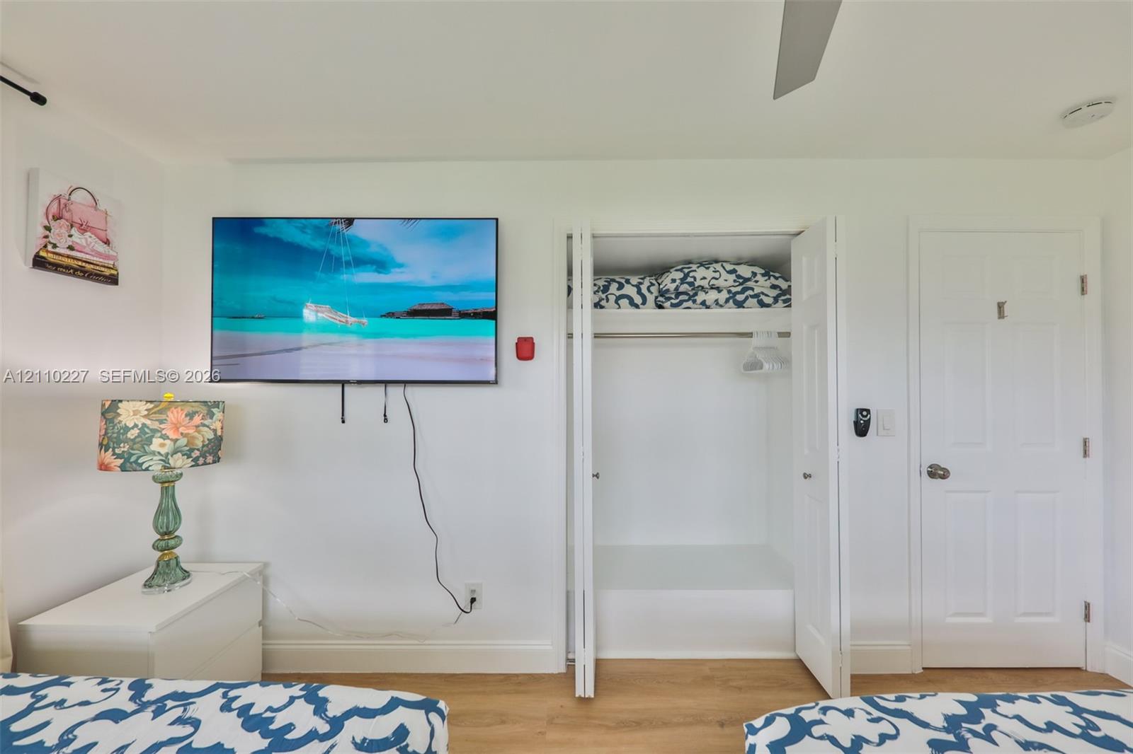 Wood-finish flooring, white four-panel interior door, and bi-fold closet doors with integrated shelving
