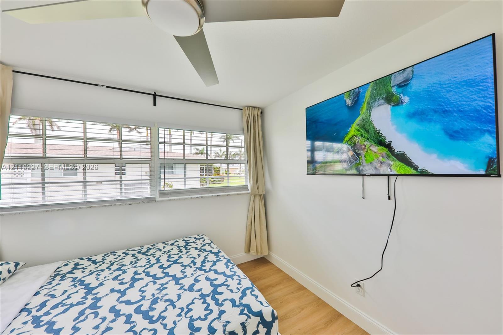 Wood-finish flooring, multi-pane horizontal windows with sills, and a central ceiling fan with integrated lighting