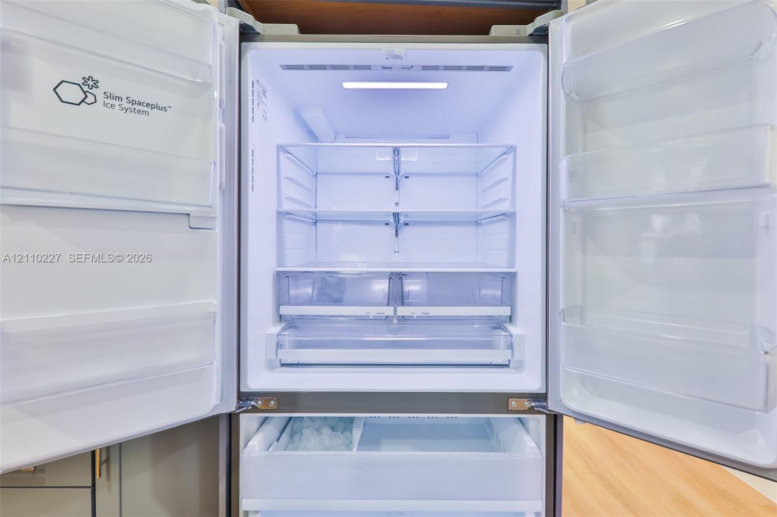 Stainless steel French door refrigerator featuring an integrated ice system, adjustable glass shelving, and humidity-controlled crisper drawers