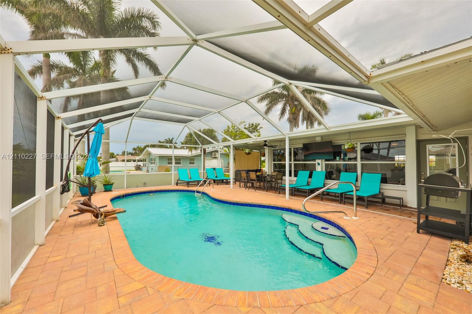 Screened-in patio featuring a paver pool deck and in-ground swimming pool with integrated stair entry