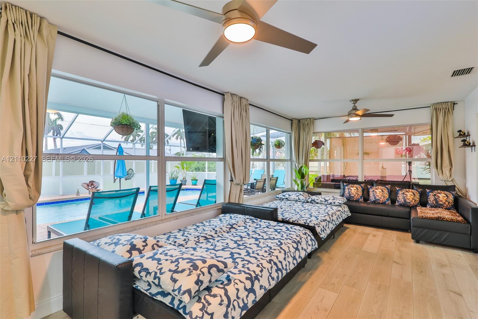 Floor-to-ceiling windows, wood-finish flooring, and dual ceiling fans