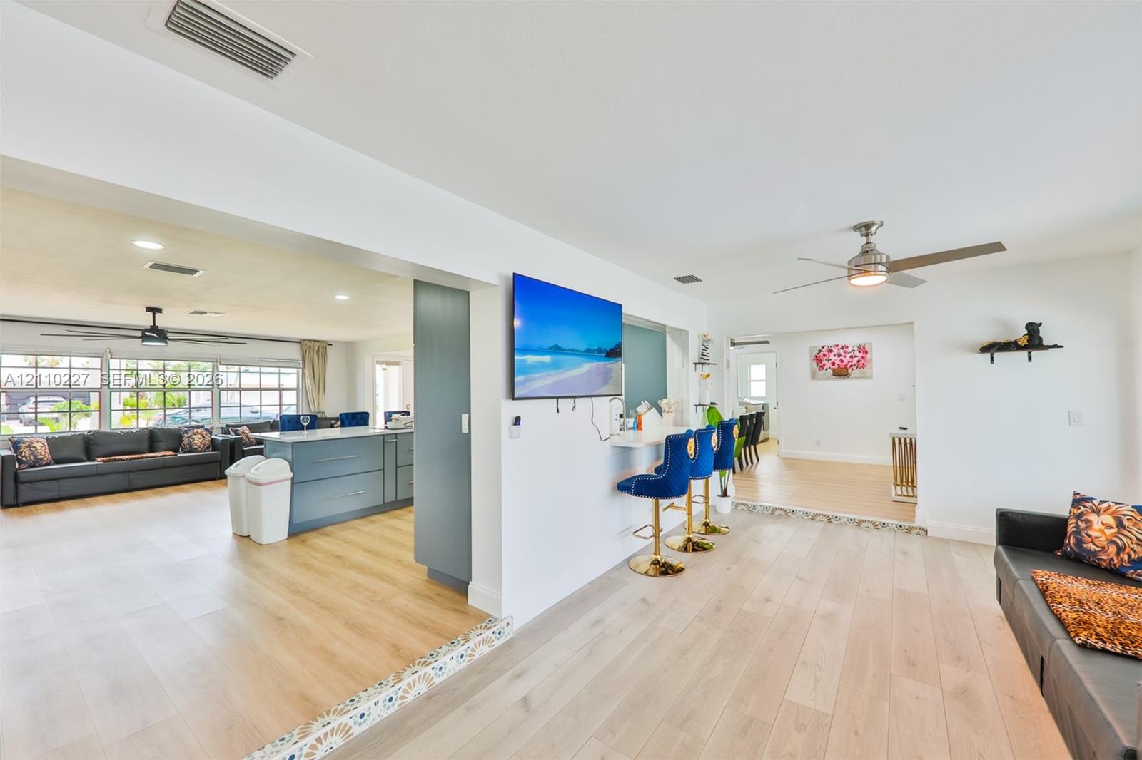 Open-concept interior featuring light wood-finish flooring, recessed lighting, ceiling fans, and a built-in counter