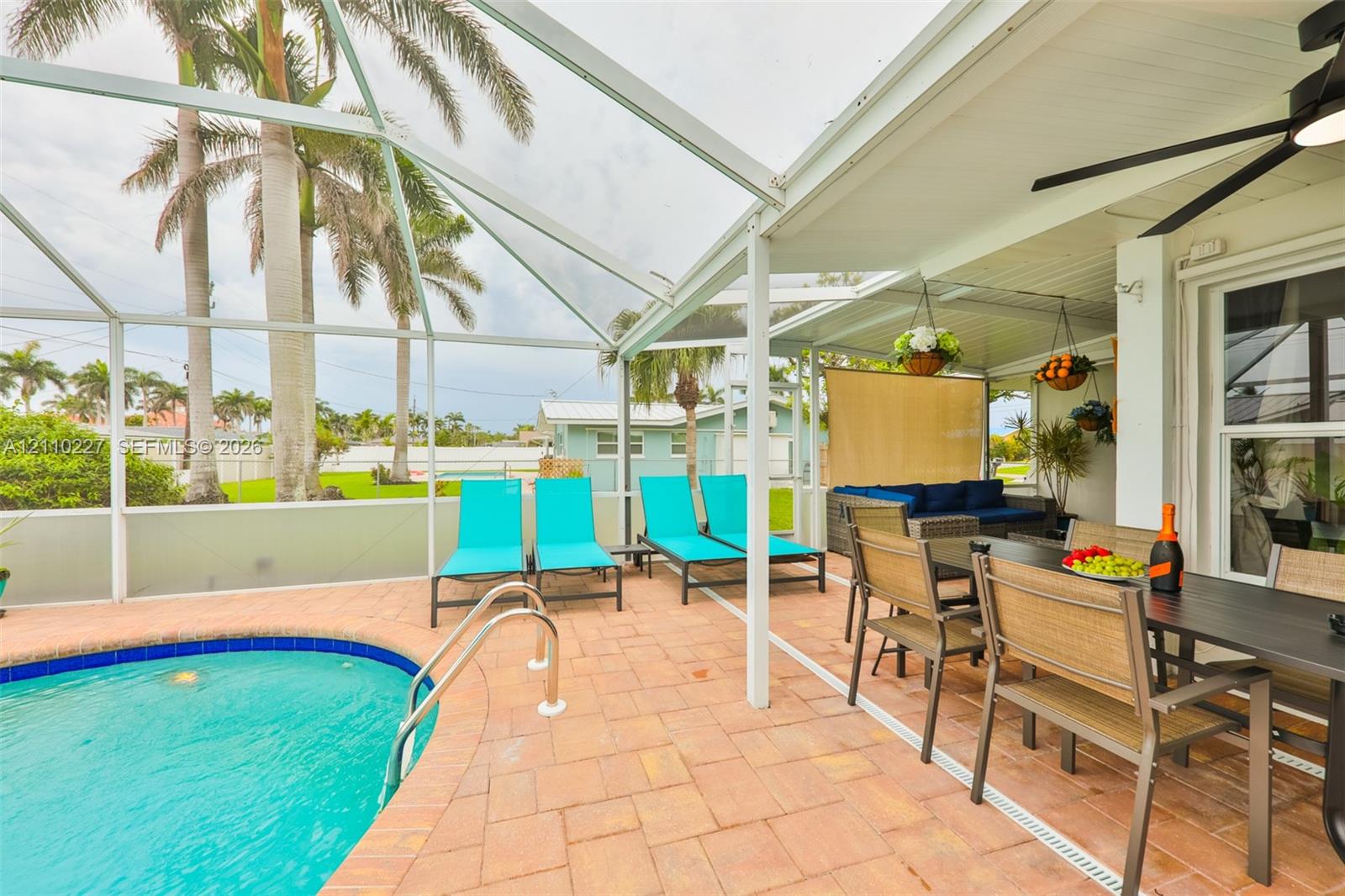 Screened outdoor living area featuring a paved pool deck, swimming pool with perimeter tiling, covered patio, and ceiling fan