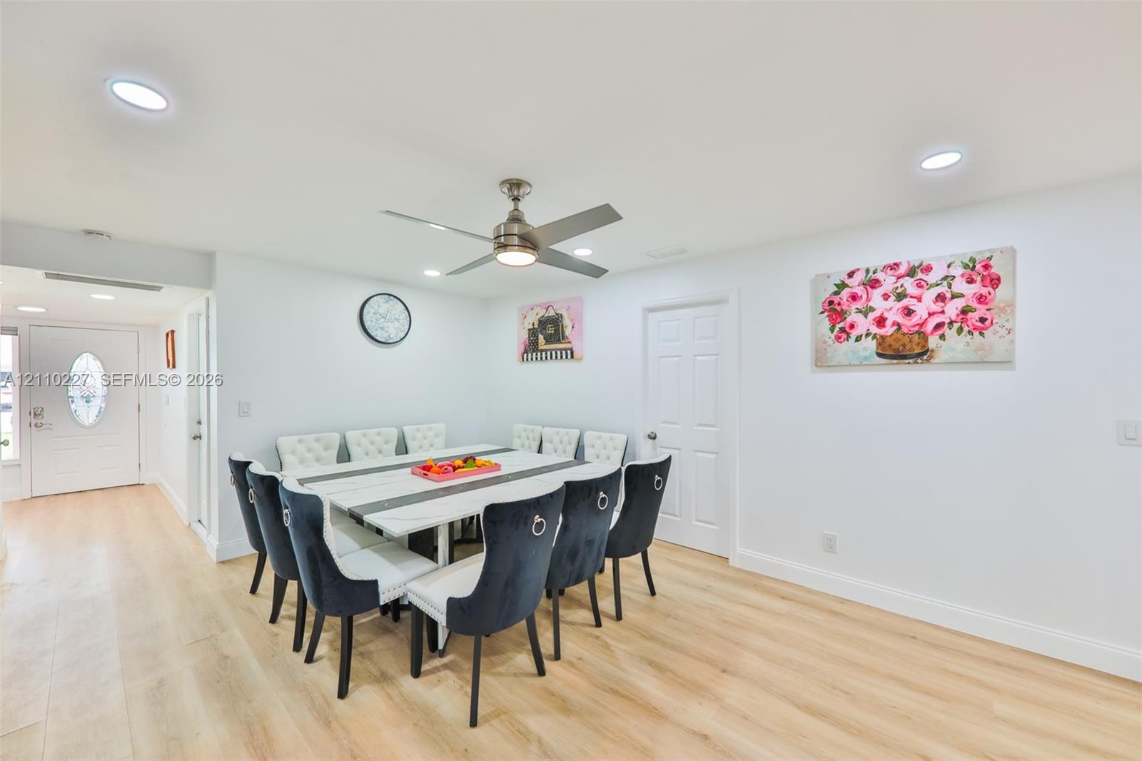 Open-concept space featuring light-toned wood-finish flooring, recessed lighting, a modern ceiling fan with integrated light, and a white six-panel interior door