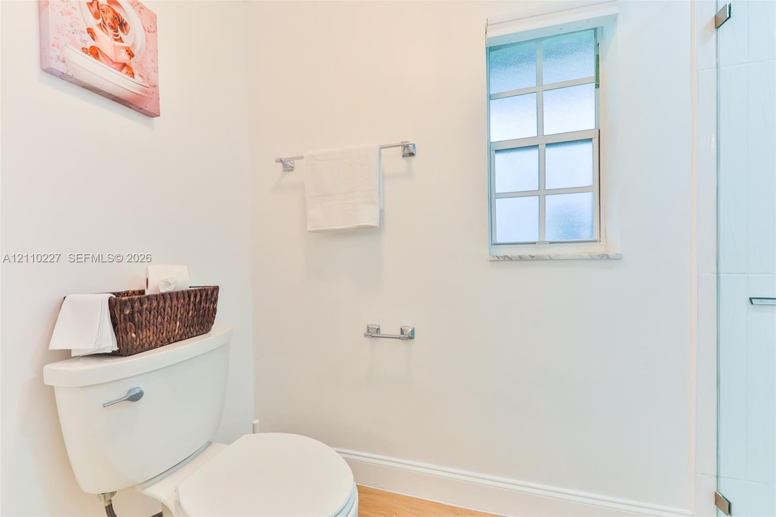 Bathroom featuring a glass-enclosed shower, multi-pane window, stone sill, and chrome hardware