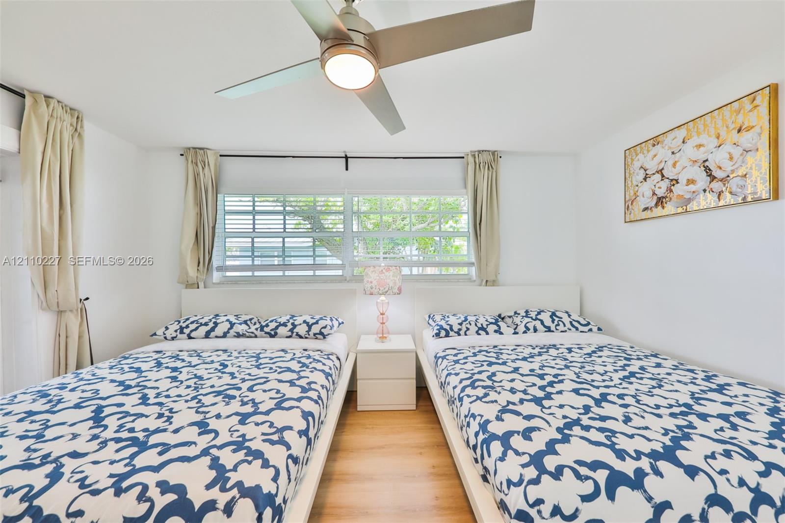 Wood-finish flooring, multi-pane windows with horizontal blinds, and a contemporary ceiling fan with integrated lighting