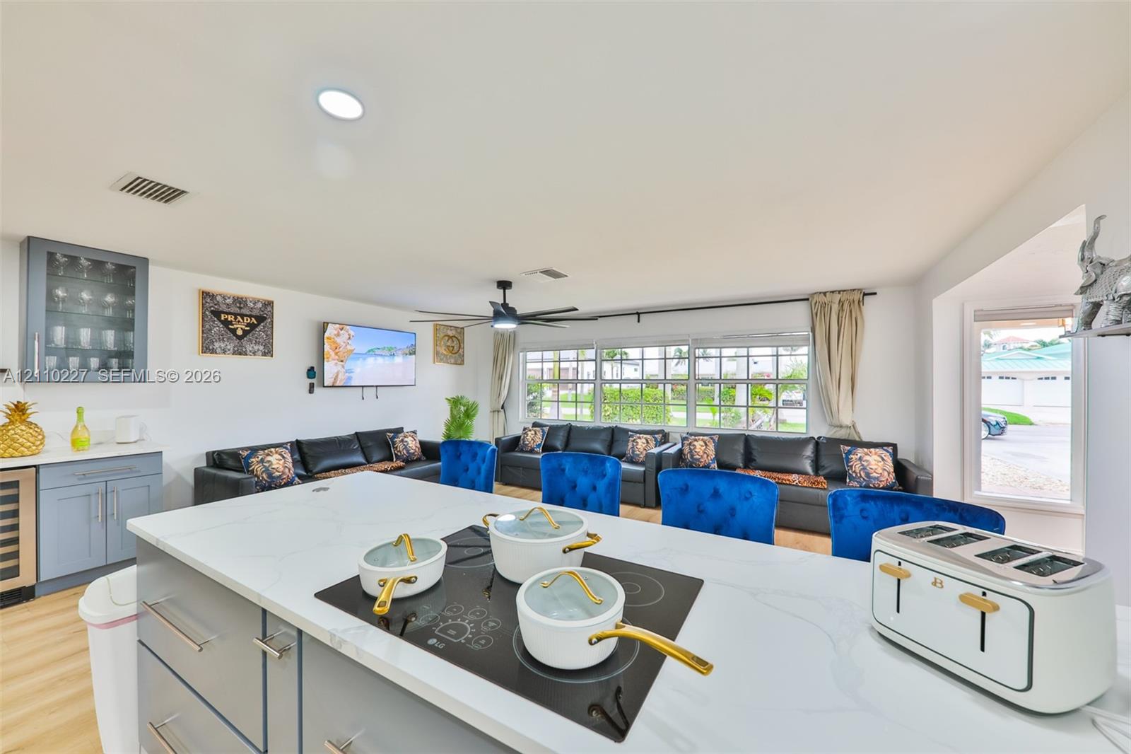 Kitchen island featuring a stone countertop, built-in cooktop, and gray cabinetry