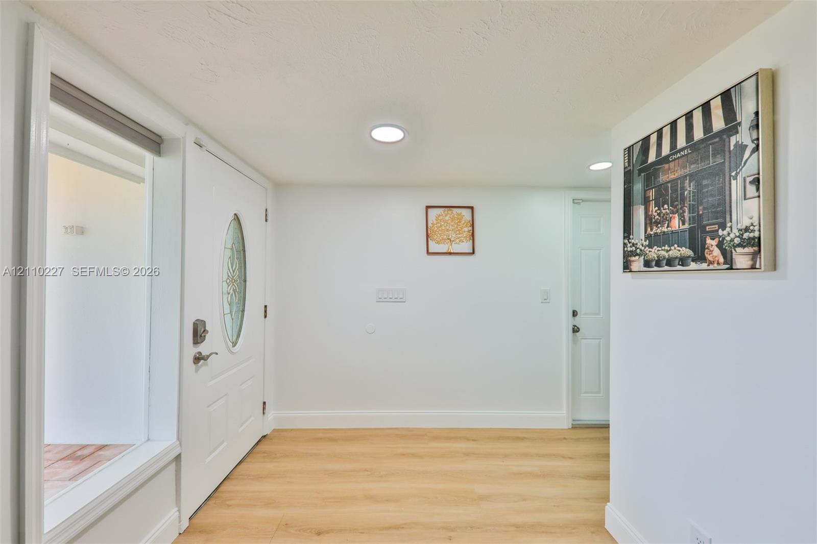 Entryway featuring light wood-finish flooring, recessed lighting, and a white six-panel door with an oval decorative glass insert