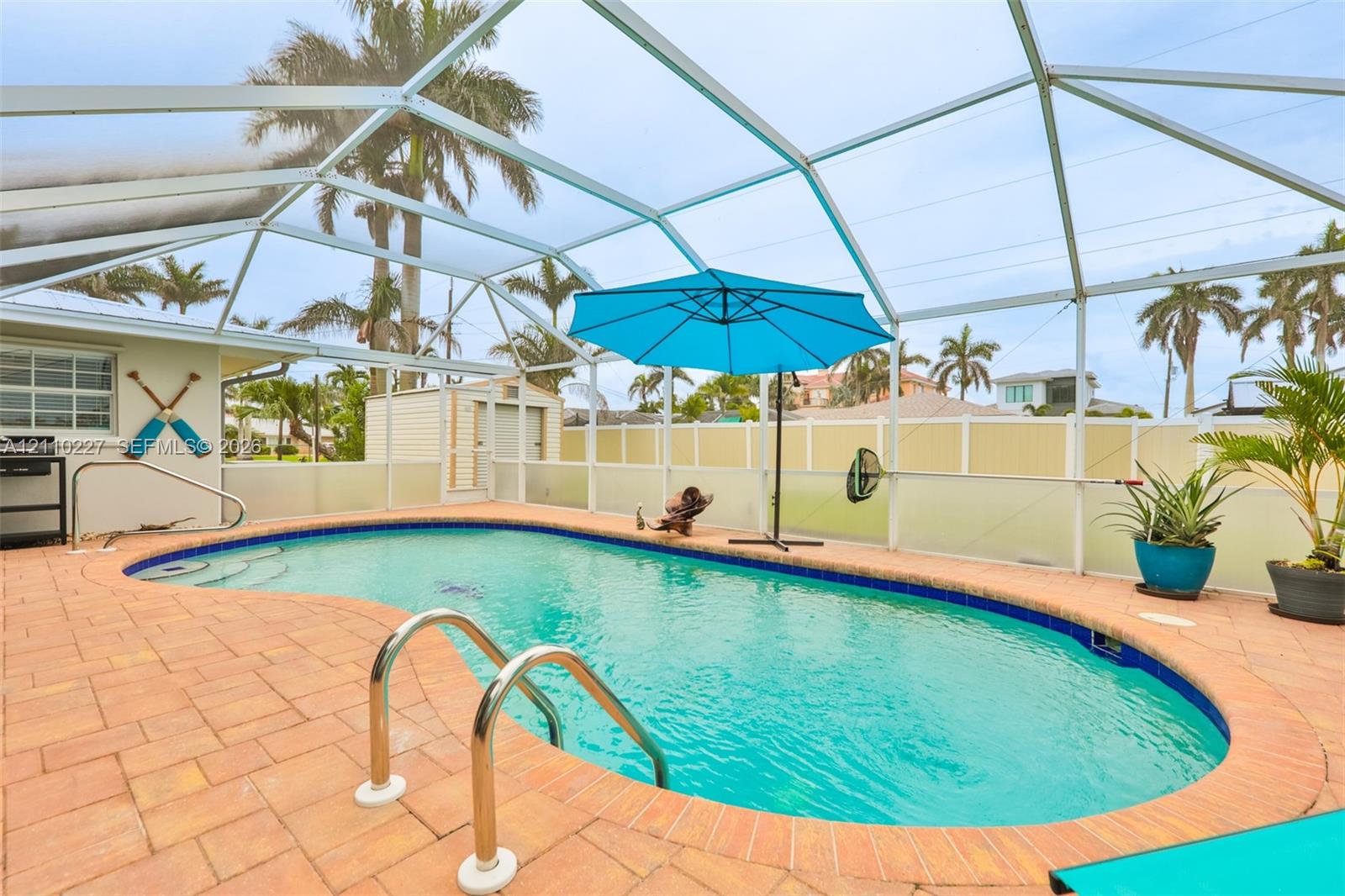 Screened-in patio featuring a kidney-shaped swimming pool, paver deck, and perimeter fencing