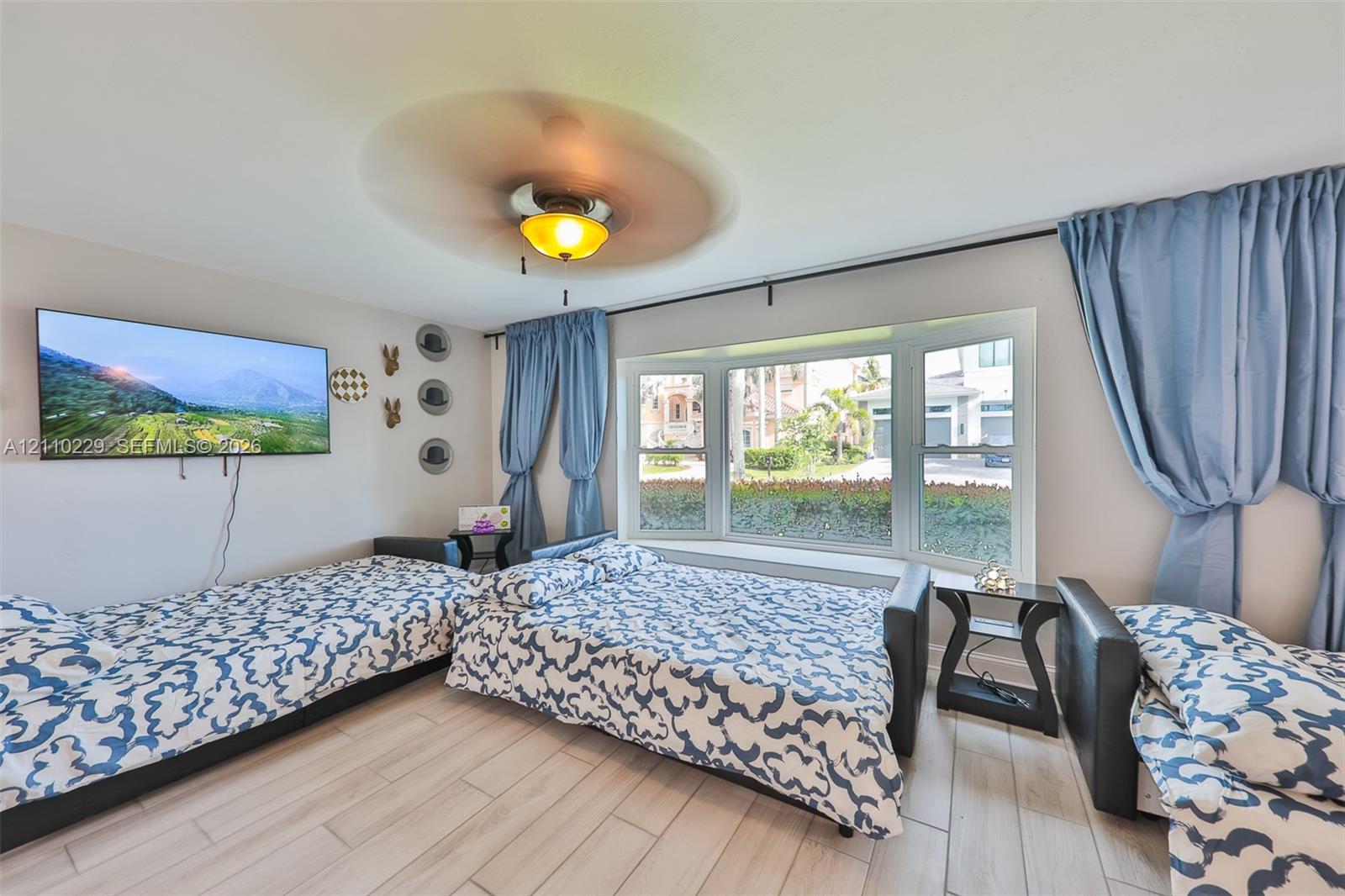 Bay window, wood-finish tile flooring, and ceiling fan with integrated lighting